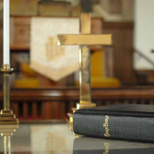 Bible on altar with candles and cross in the background