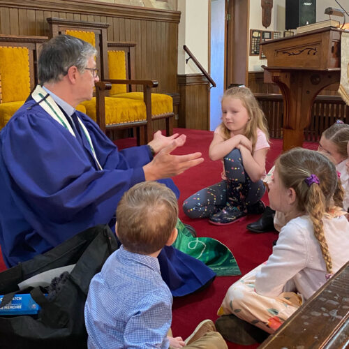 Children sitting on pulpit floor listening to Bruce for Sunday School