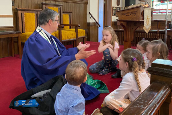 Children sitting on pulpit floor listening to Bruce for Sunday School