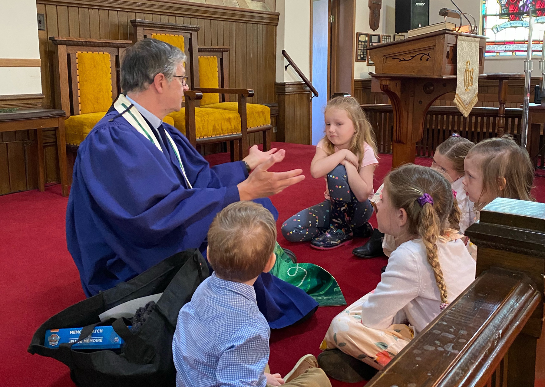 Children sitting on pulpit floor listening to Bruce for Sunday School