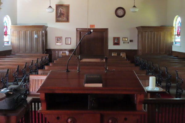 View from pulpit of bible resting on altar with pews in the background