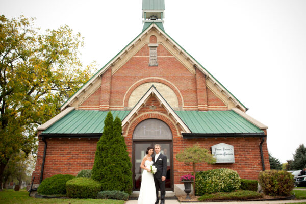 Bride and groom smiling in front of church